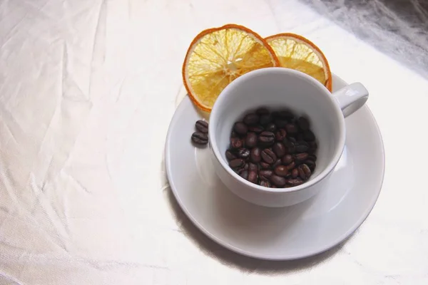 Cangkir dan piring, biji kopi, irisan jeruk kering di atas meja perak . — Stok Foto