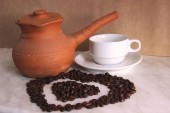 barna agyag Turk, fehér tiszta csésze és csészealj és pörkölt kávébab formájú szív a szürke asztal