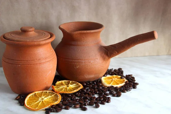 jug with handle for coffee and jug milk made of clay, a lot of roasted coffee beans and dried oranges