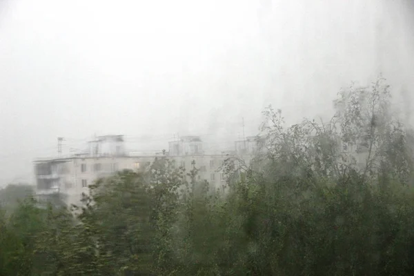 Gri, kentsel arka plan üzerinde büyük yağmur damlaları olan pencere. Pencere cam büyük ayrıntılı çok yağmur damlaları. — Stok fotoğraf