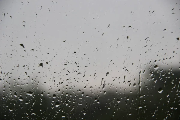 Ventana con grandes gotas de lluvia sobre un fondo urbano gris. La primera tormenta de verano . —  Fotos de Stock