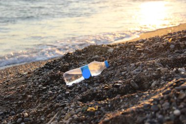 deniz kıyısı, çakıl plajı ve yarım boş su şişesi. akut çevre sorunları