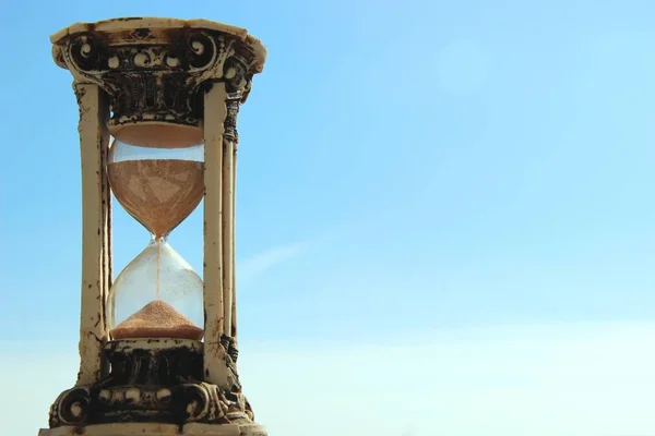 Reloj de arena contra el cielo azul y las nubes blancas. copia de espacio a la derecha — Foto de Stock