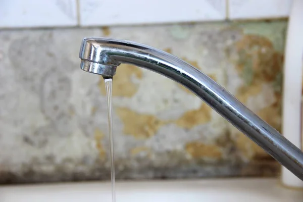 musluksu akar su ince bir dere, eski duvar arka plan üzerinde gümüş renkli mutfak musluk