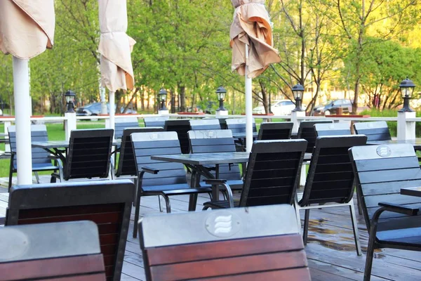 Порожні столи закритого кафе влітку. дерев'яні столи і стільці, літнє кафе, без людей перед відкриттям — стокове фото