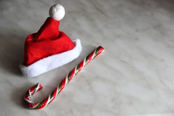 Bir kırmızı Noel Baba şapkası ve karamel kamış, gri arka plan..