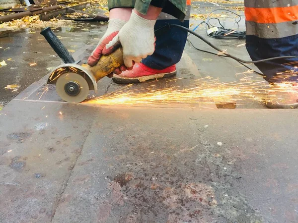 Trabajar cuando las chispas vuelan, tonificando. hombre con guantes corta una hoja de acero con una sierra circular — Foto de Stock