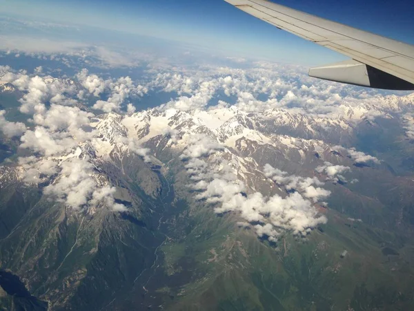 Berge und Wolken aus dem Flugzeugfenster, Flugzeugflügelelement. Handy-Foto — Stockfoto