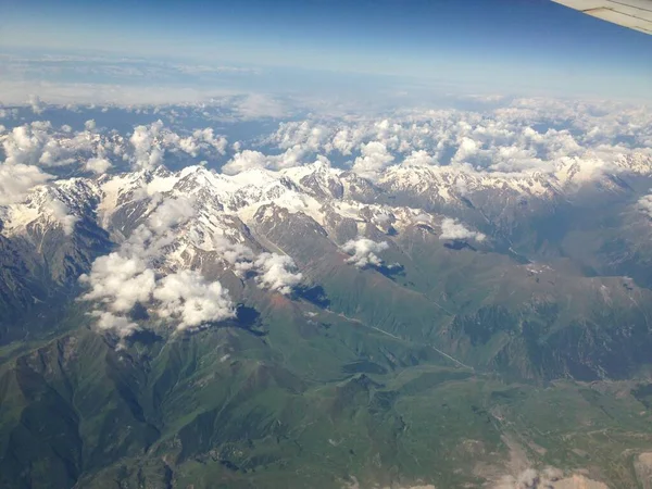 View from the plane window on clouds and mountains, aircraft wing element. mobile photo