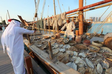 Doha - Katar / Kasım 2017: Katara sahilindeki Dhow festivali sırasında kurutulmuş ve tütsülenmiş balık satan Umman balıkçısı.