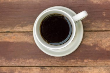 Tahta masa manzaralı bir fincan kahve.