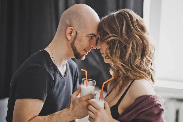 A man and a pregnant woman drink milk from glasses.