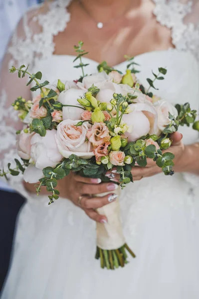 Unusual composition of the bouquet in the hands of a woman in a white dress.