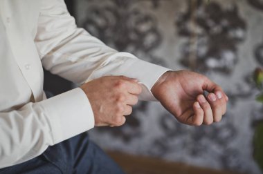 Bir adam gömleğinin kolunu bağlar..