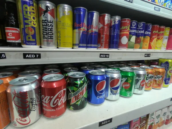 Dubai Emirados Árabes Unidos abril 2019: Várias bebidas de marca em um supermercado em Dubai. Linha ou linha de latas de refrigerantes carbonatados e exibição de bebidas energéticas para venda nas prateleiras do supermercado . — Fotografia de Stock