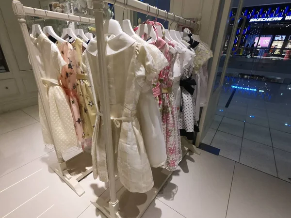 Dubai Emirados Árabes Unidos julho 2019: Uma fileira de roupas infantis penduradas em cabides. Roupas infantis dentro de uma loja. Uma vista de vestidos de criança coloridos e vestidos pendurados no rack de pano na loja. — Fotografia de Stock