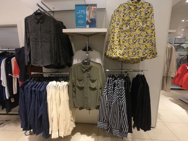 Dubai Emirados Árabes Unidos: julho 2019 - Vendas, desconto e compras no shopping de moda, escolhendo roupas novas. Roupas penduradas para venda no shopping. Roupa feminina colorida, conjunto diferente em prateleiras na loja de roupas . — Fotografia de Stock