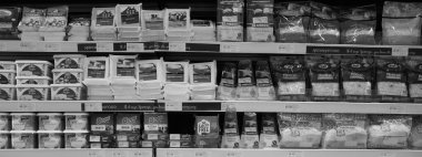 Marketteki raflardaki farklı peynirlerin siyah ve beyaz görüntüsü. Pazarda paketlenmiş ürünler, tereyağı ve peynir rafı. Çedar, Edam, Mozzarella peyniri. Dubai BAE Aralık 2019