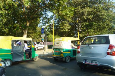 Hint Yolu 'nda gündüz vakti araba, otomobil ve bisiklet trafiği. İnsanlar ağaçların altında güneş ışığından uzakta duruyorlar. : Punjab India - Mayıs 2020