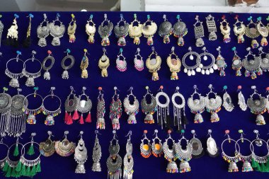 Udaipur Hindistan 'daki sokak pazarında turistler için mavi arka planda asılı renkli el yapımı küpeler. Sokak pazarında satılık renkli el yapımı güzel ve şık küpeler. 34