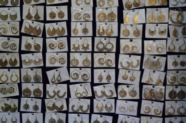 Yerel pazarda satılmak üzere küçük plastik torbalarda saklanmış Hint küpeleri. Hindistan 'da bir kuyumcunun tezgahında yapılmış çeşitli küpeler. Sokak pazarının dışında bir sürü renkli küpe var. F9EN