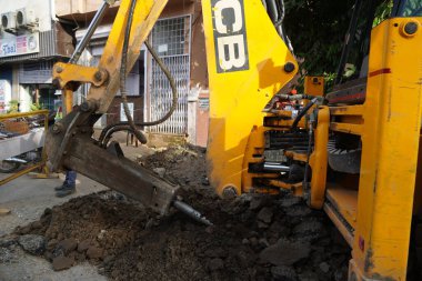 JCB toprak hareket makinesi yolda çalışıyor. JCB kova doldurucu toprak yolun bir bölümünü onarıyor. Yol yerleşim bölgesinde genişliyor. Yol yapımı teması. : Udaipur Hindistan Haziran 2020 0AL