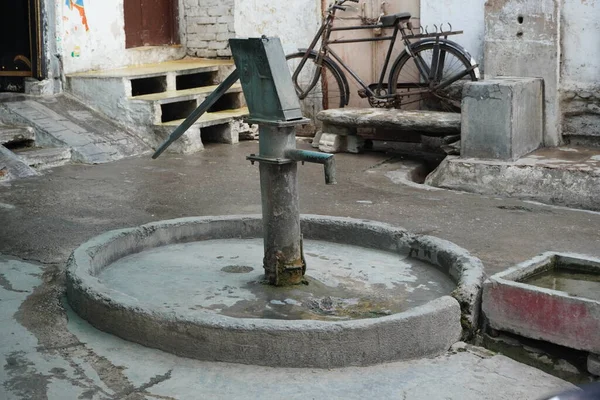 Old hand operated water pump and water containers in rural India. Hand water pump in old city. Very Old Vintage Hand Manual Pump. PEG