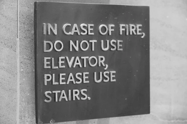 一个标牌上写着 发生火警时 请勿使用电梯 请使用楼梯 楼梯指示人们在火警紧急情况下该怎么做 黑白照片 Vo4M 图库图片