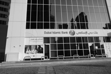 Dubai BAE Aralık 2019 - Dubai İslami Bankası, güneşli bir günde büyük bir binanın tepesinde büyük bir Orta Doğu bankası logosu inşa ediyor. Banka şubesinin önünde. Siyah beyaz fotoğraf. DLG