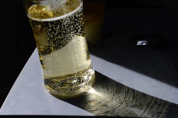 Kieliszek szampana z promieniem słońca złowionego z iluminator na pokładzie samolotu na rozkładanym stole — Zdjęcie stockowe