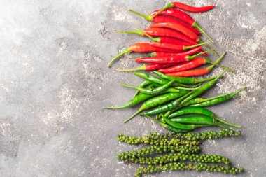 Farklı türde kırmızı yeşil gri bir arka plan üzerinde siyah biber. Düz düzen. Uzay kopyalayın. Yukarıdan görüntülemek.