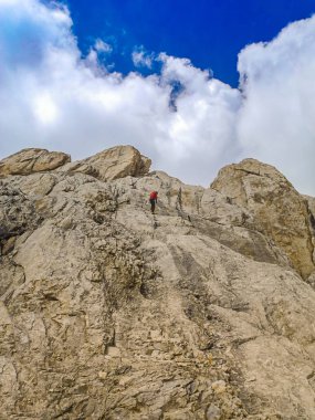 Bir adam tırmanıcı kayalık üstten zirveye tırmanıyor. Aşırı rekreasyon ve macera kavramı.