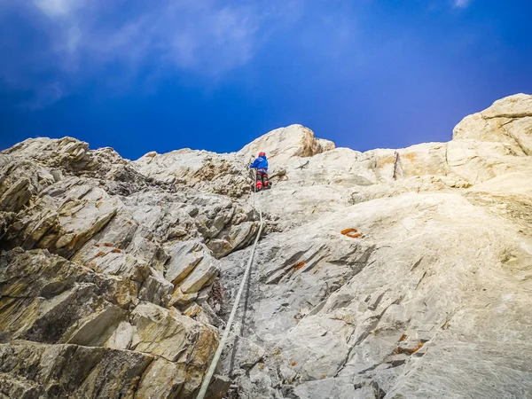 A man climber climbs the rocky ledges to the top. The concept of extreme recreation and adventure.