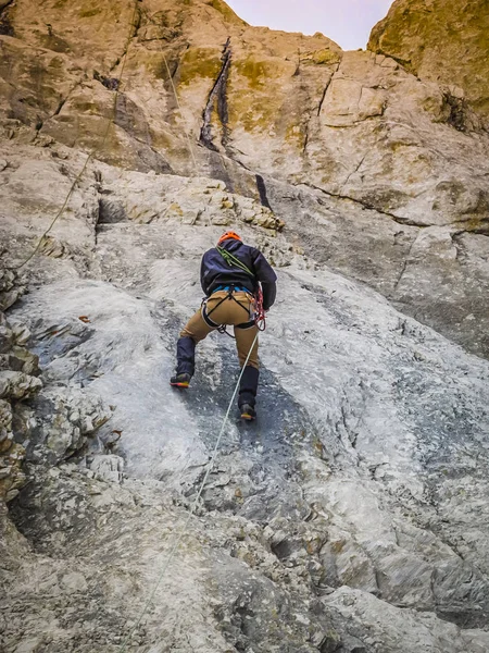 A man climber climbs the rocky ledges to the top. The concept of extreme recreation and adventure.