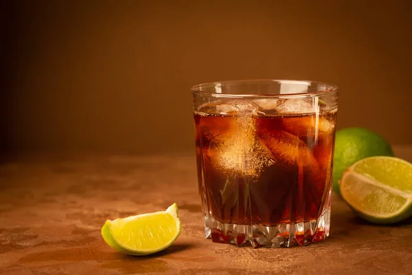 Cocktail van rum ijsblokjes en limoen in glas Goblet op een donker bruine achtergrond. Sterke alcoholische drank. Ruimte kopiëren. — Stockfoto
