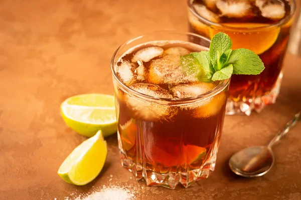 Cocktail av Rom och Cola isbitar och lime i ett glasbägare på en mörkbrun bakgrund. Stark alkoholhaltig dryck. — Stockfoto