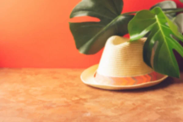 El sombrero veraniego de la paja clara sobre el fondo coralino con las hojas de la planta tropical. Concepto de recreación y viajes . —  Fotos de Stock