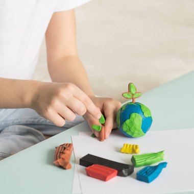 Çocuk plastikin dünya ve ağaçlar sculpts. Çocuk avuç içinde gezegenin konumu. Ekoloji konsepti.