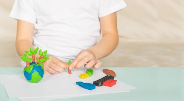 Çocuk plastikin dünya ve ağaçlar sculpts. Çocuk avuç içinde gezegenin konumu. Ekoloji konsepti.