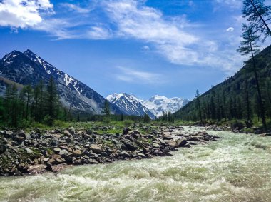 Altai karla kaplı dağların eteklerinde fırtınali dağ nehri. Seyahat kavramı ve aşırı rahatlama.