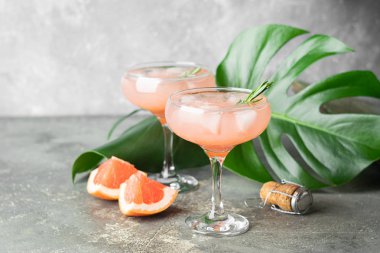 Gri beton arka plan üzerinde iki zarif cam kadehler içinde greyfurt biberiye ve buz iç. Serinletici yaz kokteyli