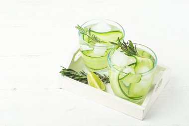 Taze salatalık sulu limon ve biberiye beyaz bir arka plan üzerinde cam bardaklarda fışkın iç. Seçici odak.