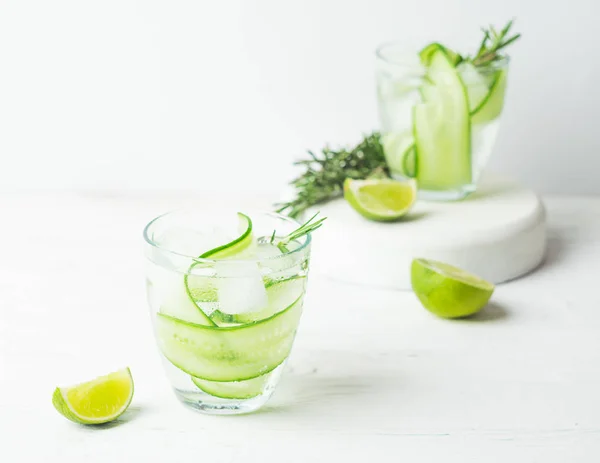 Drink from fresh cucumber juicy lime and a sprig of rosemary in glass glasses on a white background. Selective focus. — Stock Photo, Image