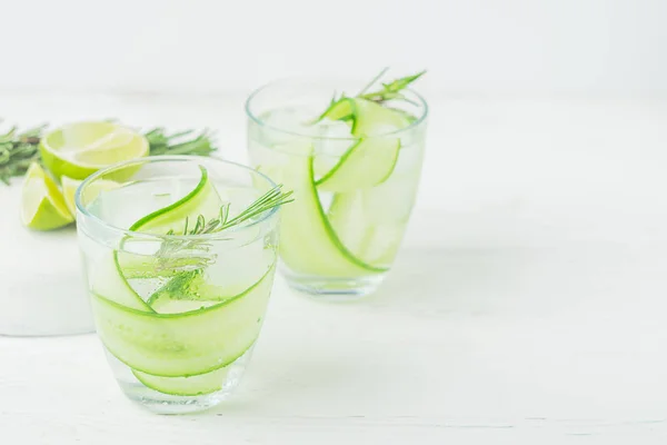 Drink from fresh cucumber juicy lime and a sprig of rosemary in glass glasses on a white background. Selective focus. — Stock Photo, Image