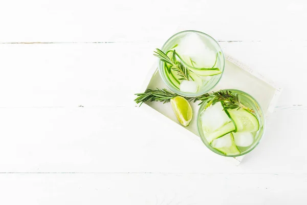 Drink from fresh cucumber juicy lime sprig of rosemary in glass glasses on a white background. Summer refreshing detox. — Stock Photo, Image