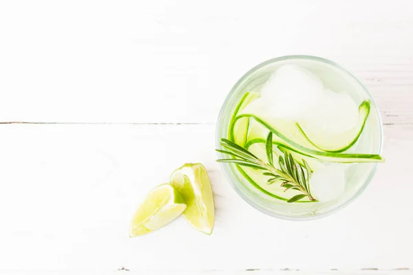 Drink from fresh cucumber juicy lime and sprig of rosemary in a glass goblet white background. Summer refreshing detox. — Stock Photo, Image