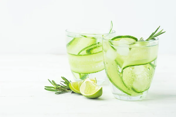 Drink from fresh cucumber juicy lime and a sprig of rosemary in glass glasses on a white background. Selective focus. — Stock Photo, Image