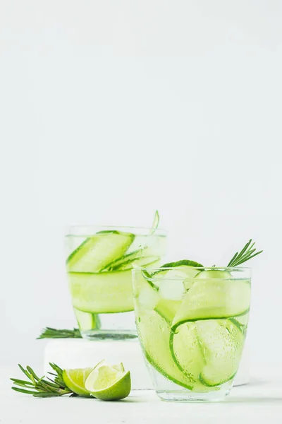 Drink from fresh cucumber juicy lime sprig of rosemary in glass glasses on a white background. Summer refreshing detox. — Stock Photo, Image