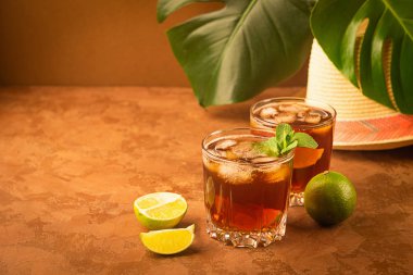 Soğuk buz küpleri ve nane ile iki cam kadehler koyu kahverengi arka planda çay. Alkollü veya alkolsüz mahito.