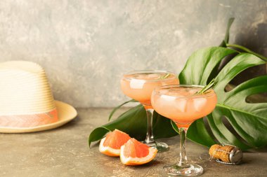 Şampanya greyfurt suyu iki cam kadehler canavar bir beton zemin bırakır ve bir yaz şapka yenileniyor.